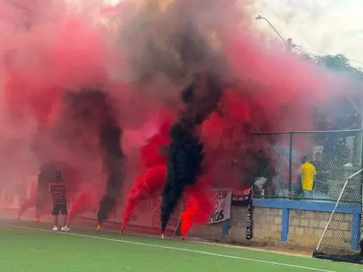 Hinchas del Mengao Baranoa F.C. con humo rojo y negro en la tribuna
